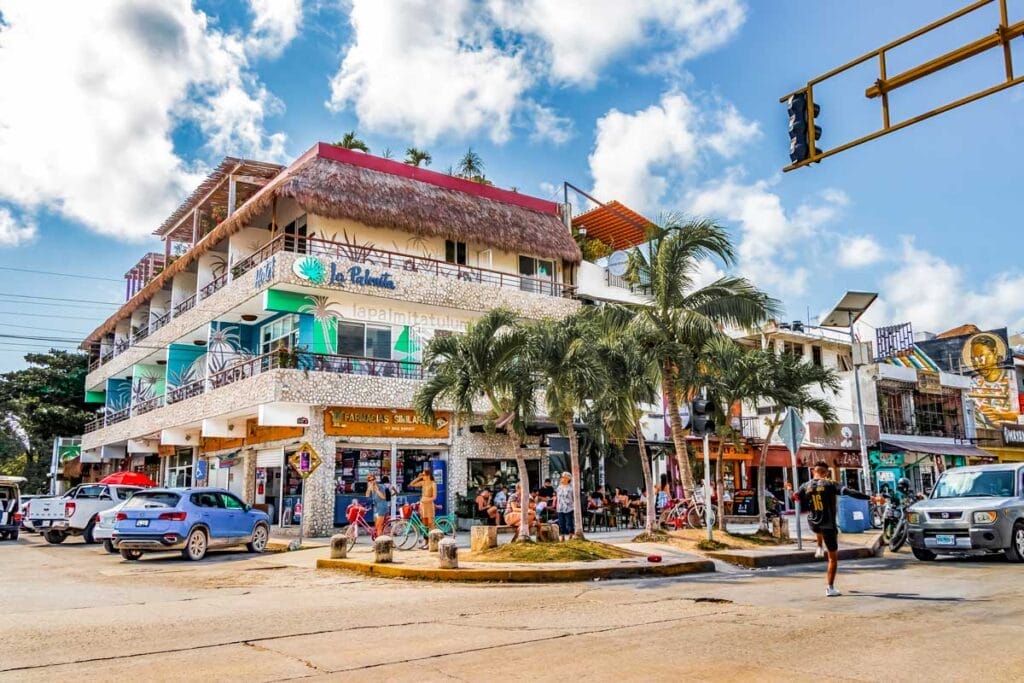 Vibrant street in Tulum Pueblo featuring colorful murals, local shops, and pedestrians enjoying the lively atmosphere.