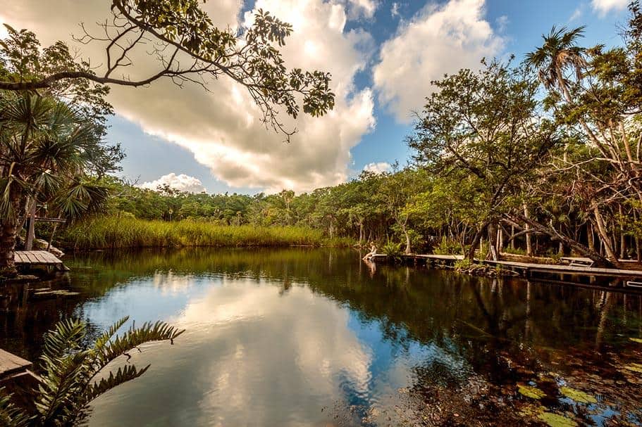 cenote corazon tulum - a girl sitting on a platform by the edge. - Cancun Cenotes