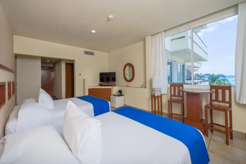 standard room at Ixchel Beach Hotel with two beds and a table and chairs in front of the window