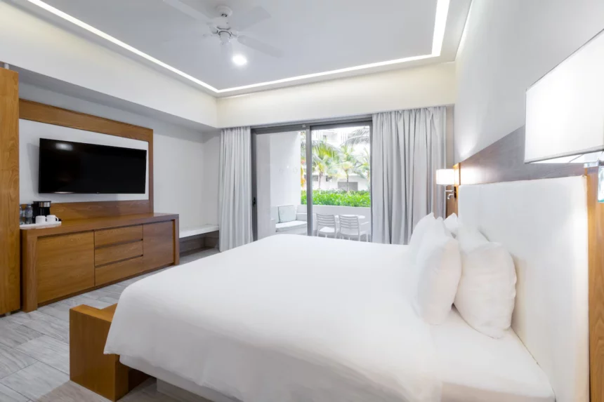 white bed at izla hotel facing a flat screen tv mounted on the wall with glass door to patio