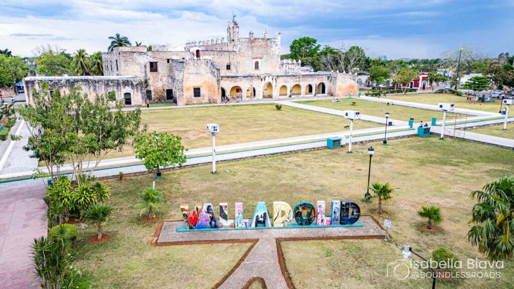 The image shows Convent de San Bernardino de Siena, Valladolid, with lush gardens and colorful "Valladolid" sign in the foreground.