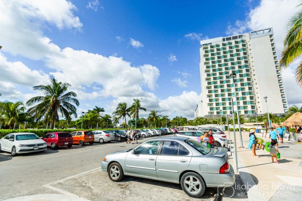 Parking lot with palm trees and tall building.